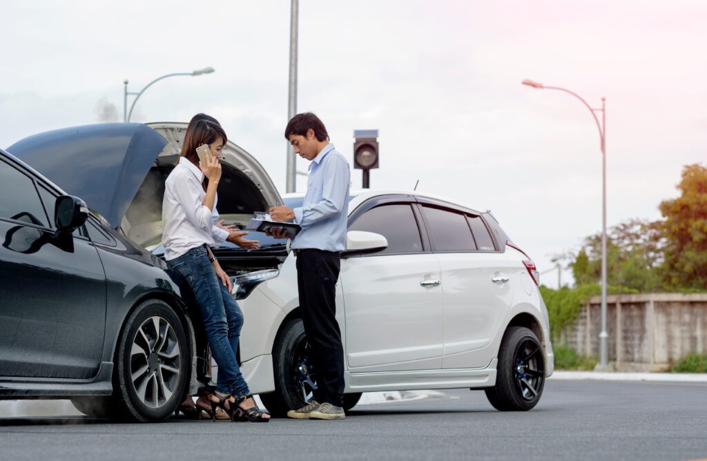 Woman driver calls for instruction during insurance agent review the dammage of the car after accident